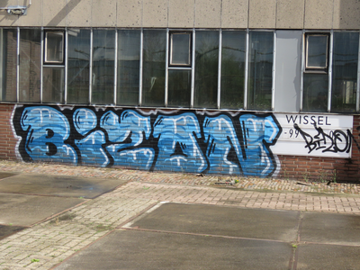 829803 Afbeelding van graffiti met een gestileerde tekst, op de plint van een voormalige werkplaats van de N.S. op het ...